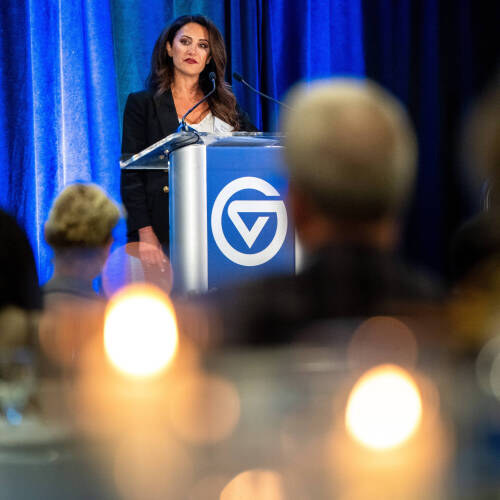 A woman at a podium with candles in the foreground.